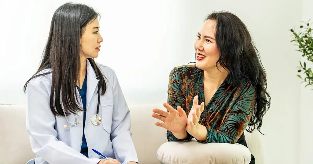 Patient speaking with a female doctor in a relaxed setting, representing an open conversation about the safety, risks, and expectations of Lipo 360 surgery.