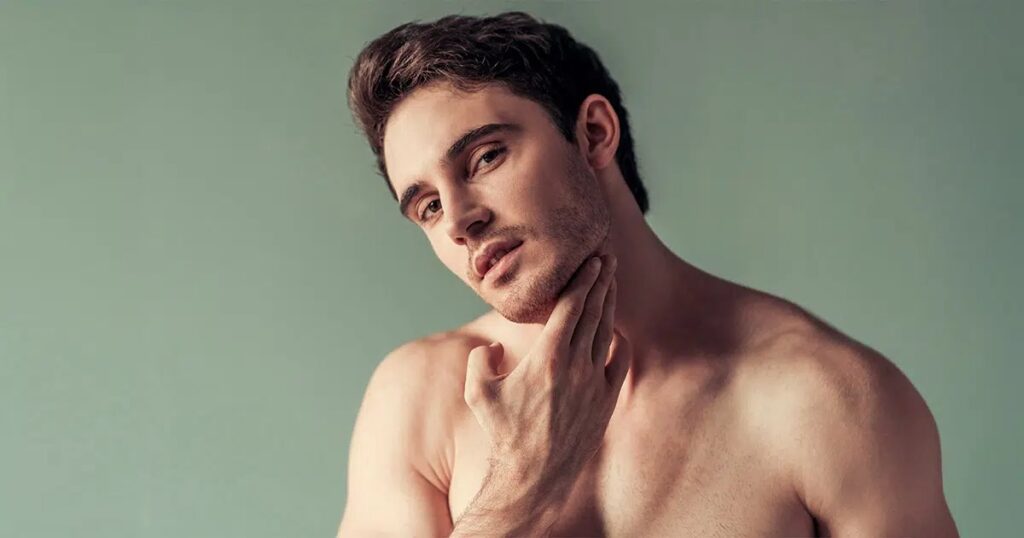 Shirtless man touching his chin and jawline, representing preparation or consideration for chin liposuction surgery.