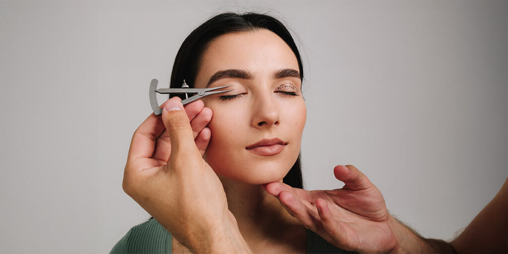 Woman undergoing a cosmetic consultation with calipers measuring her eyelid for ptosis correction procedure.