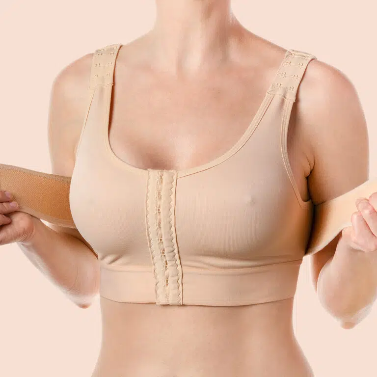 Woman in a beige front-closure bra holding a wide elastic band across her chest