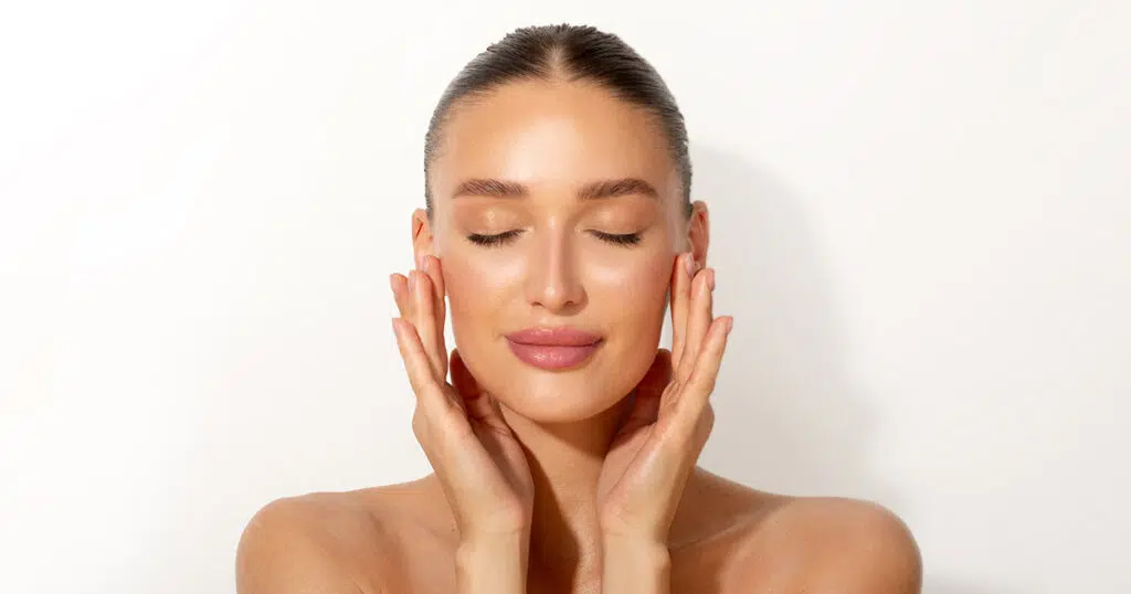 Woman with closed eyes touching her cheeks with her fingertips