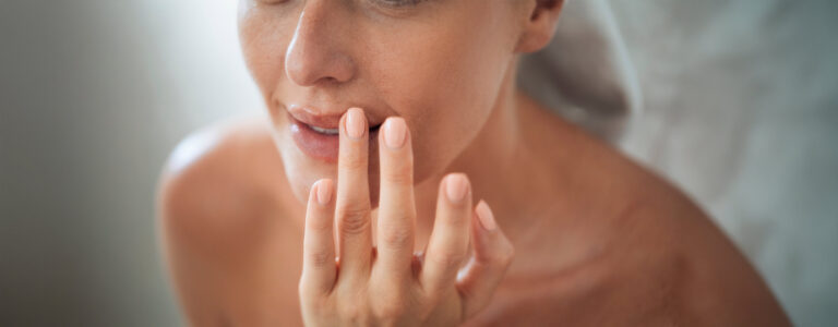Close-up of a woman gently touching her upper lip, the area addressed by a lip lift