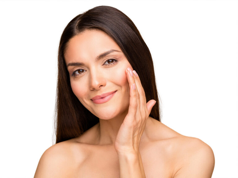Smiling woman with smooth skin touching her cheek with one hand
